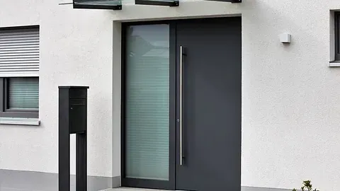 Moderne inngangsdør i mørk grå farge med smalt vindusfelt og minimalistisk design